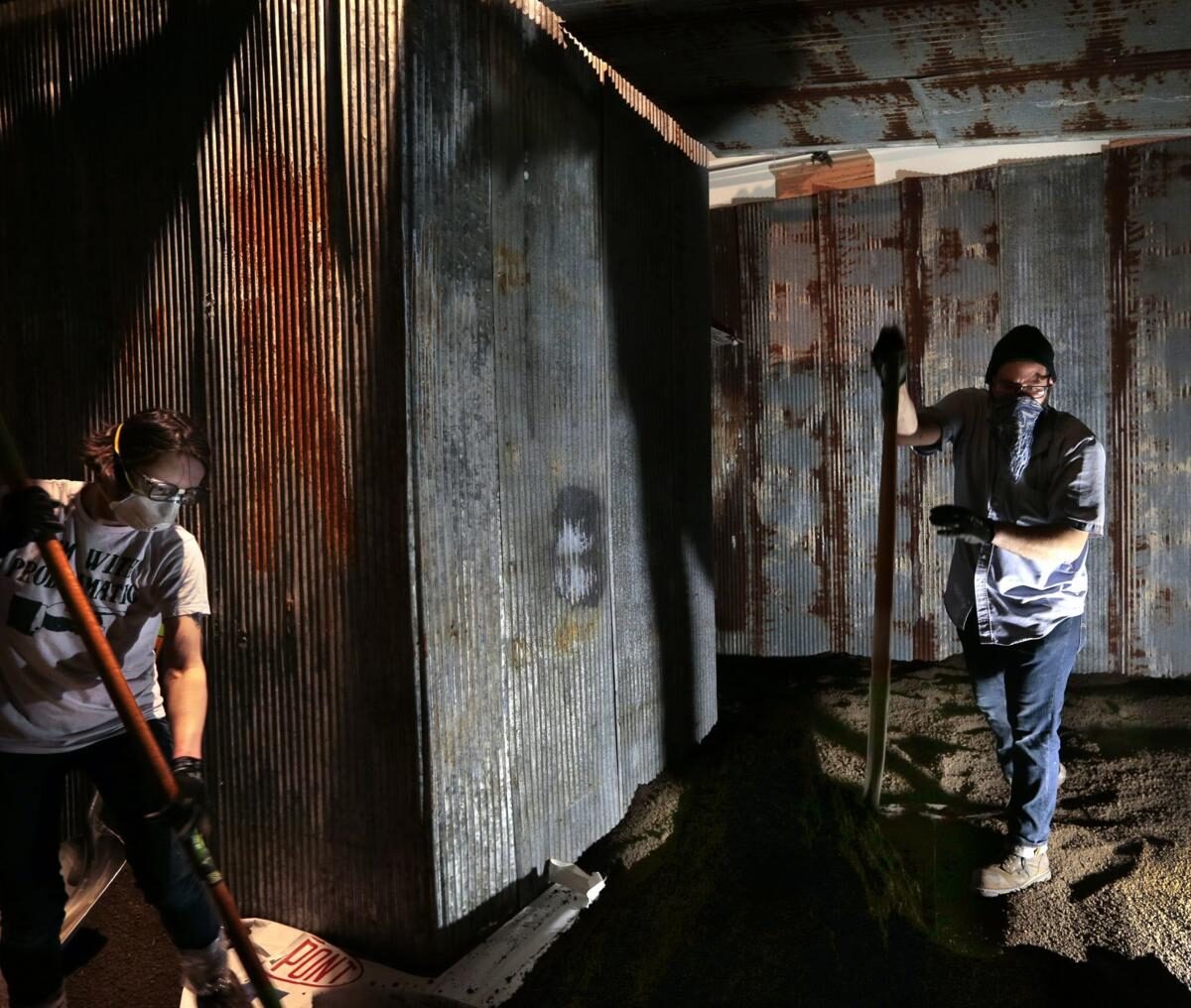 Jen Nugent and Caleb Hauck shovel dirt into Derek Fordjour's installation <em>SHELTER</em>. Photo: Robert Cohen, <em>St. Louis Post-Dispatch</em>